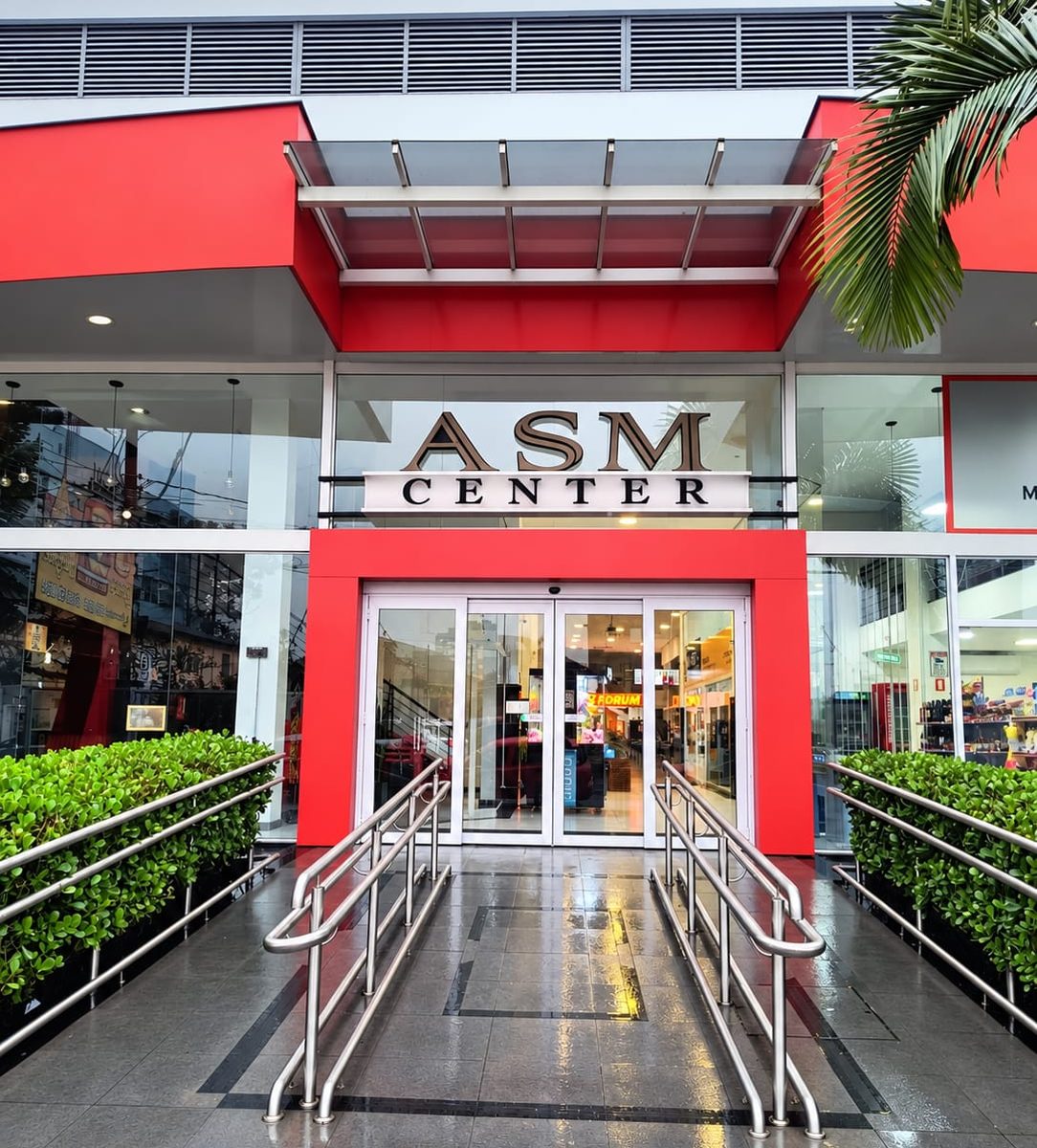 Entrada do ASM Center, na Rua Dom Pedro, com o letreiro do Xis do Fórum visível ao fundo pelas portas de vidro